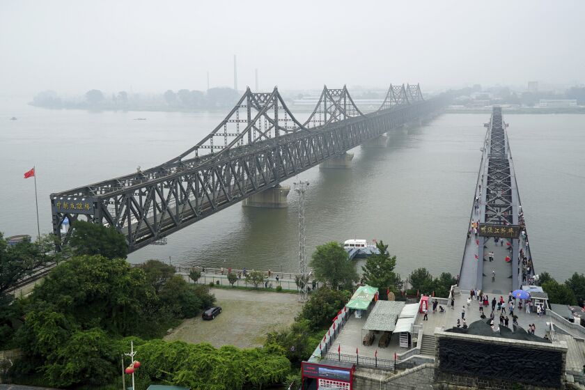FILE -Visitors walk across the Yalu River Broken Bridge, right, next to the Friendship Bridge connecting China and North Korea in Dandong in northeastern China's Liaoning province, Sept. 9, 2017. North Korea and China resumed freight train service Monday, Sept. 26, 2022, following a five-month hiatus, South Korean officials said, as the North struggles to revive an economy battered by the pandemic, U.N. sanctions and other factors. (AP Photo/Emily Wang, File)