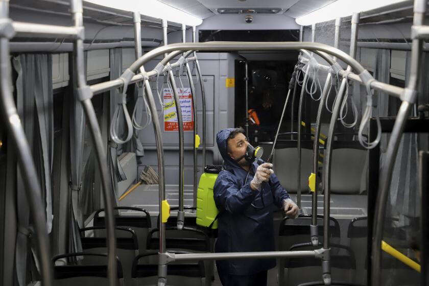 A worker disinfects a public bus against coronavirus in the city of Ahvaz in southwestern, Iran, in early morning of Tuesday, Feb. 25, 2020. Iran's government said Tuesday that more than a dozen people had died nationwide from the new coronavirus, rejecting claims of a much higher death toll of 50 by a lawmaker from the city of Qom that has been at the epicenter of the virus in the country. (Alireza Mohammadi/ISNA via AP)