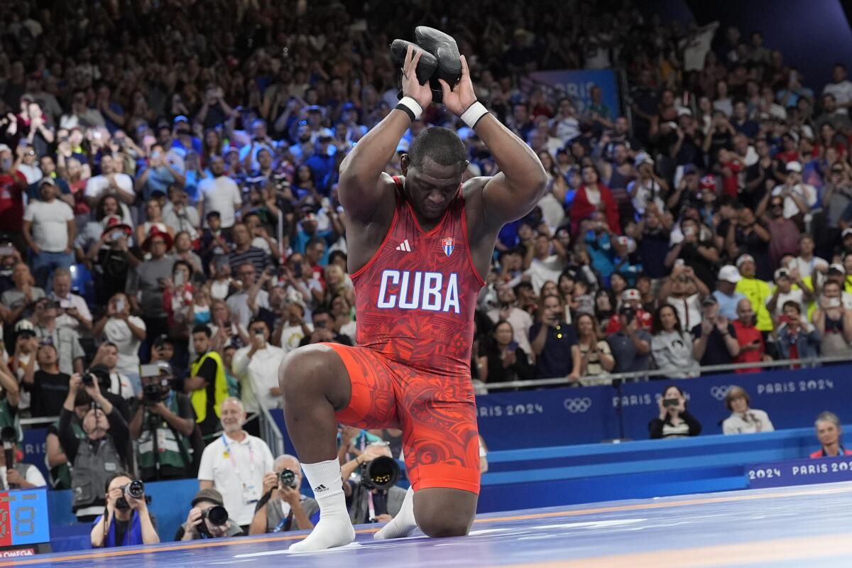 Cuba's Mijain Lopez Nunez removes his shoes as a signal he is retiring after beating Chile's Yasmani Acosta Fernandez