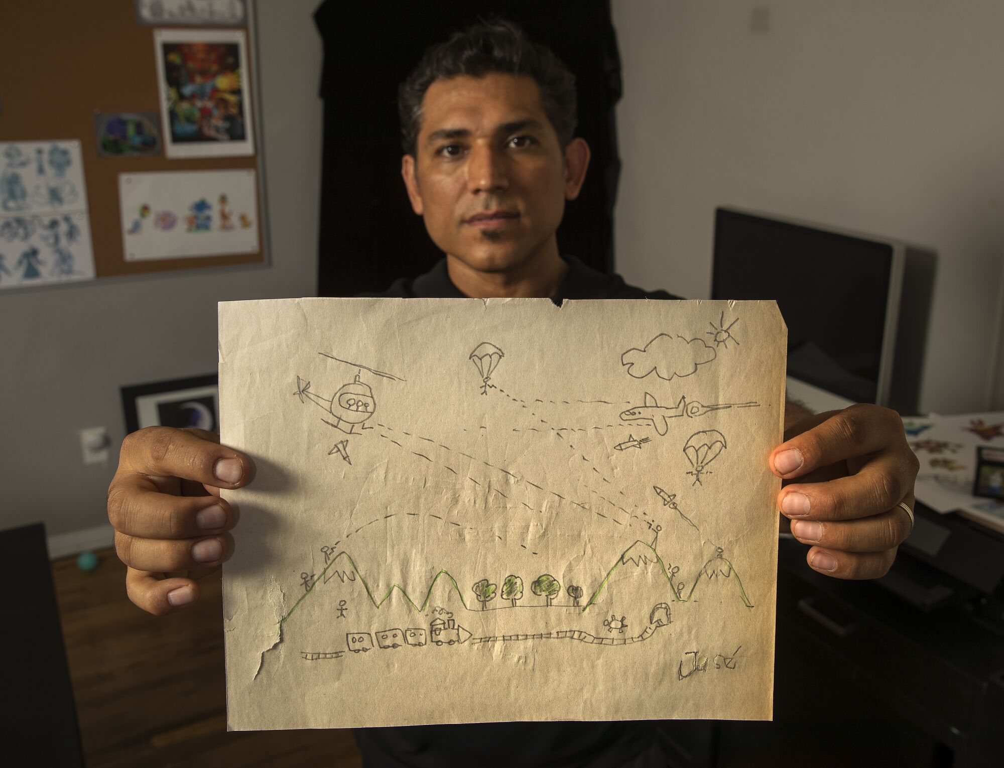 Disney character designer Jose Zelaya holds a drawing he did as a boy, depicting the war in El Salvador, where he grew up. 