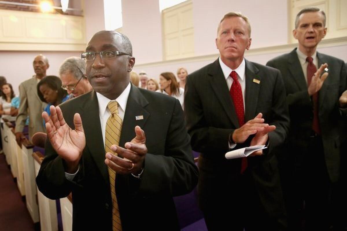 Sanford Police Chief Cecil Smith, left, and Mayor Jeff Triplett, center, attend a prayer vigil in the wake of the George Zimmerman trial. The chief is moving to overhaul the city's neighborhood watch program.