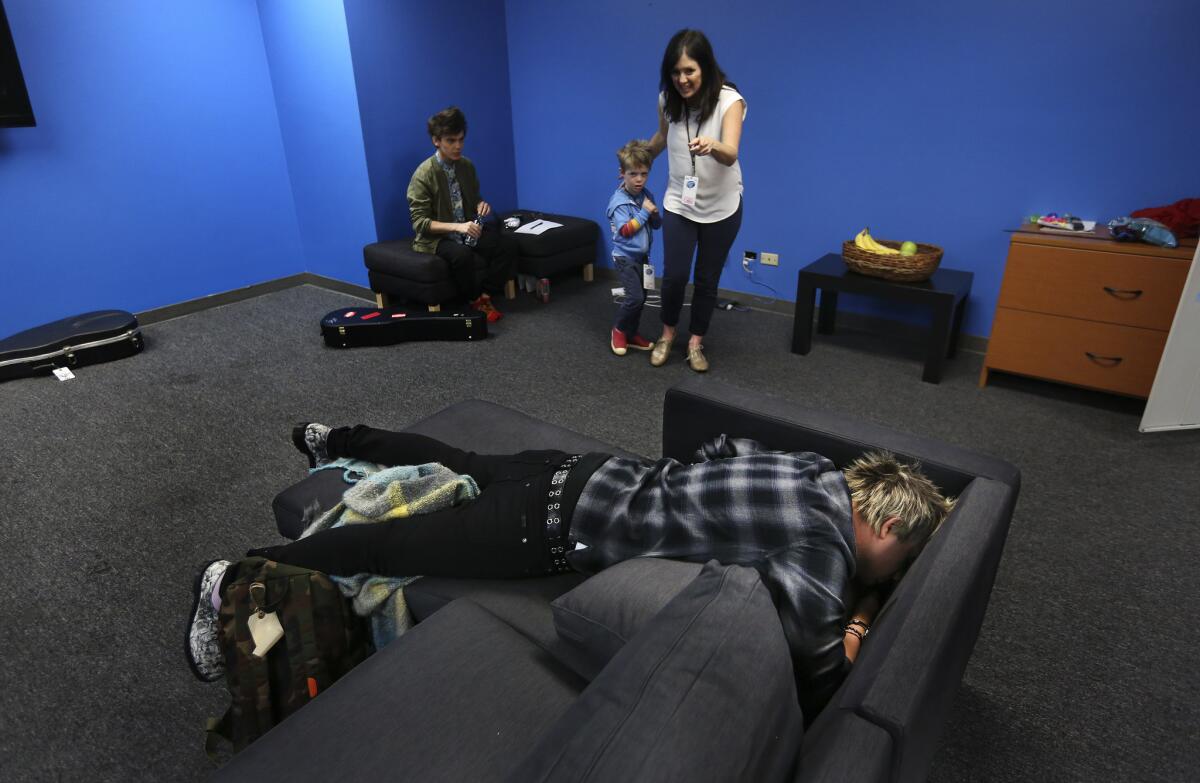 Co-executive producer Megan Wolflick, center, and her son, Leo, 3, look on as "American Idol" contestant Dalton Rapattoni gets some rest inside the contestants lounge before the start of a dress rehearsal at CBS Television City in Hollywood. At far left is contestant MacKenzie Bourg.