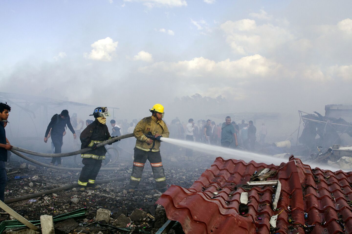 Firefighters put out embers amid the debris of the fireworks market.