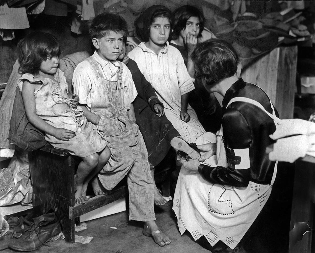 March 14, 1928: A Red Cross worker helps find shoes for children forced from the homes by the collapse of St. Francis Dam.