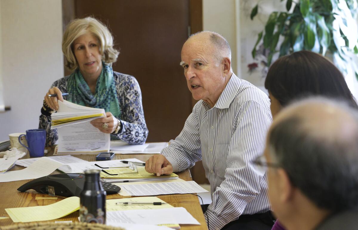 Gov. Jerry Brown discusses a bill while meeting with advisors at his Capitol office in Sacramento. At left is advisor Nancy McFadden.