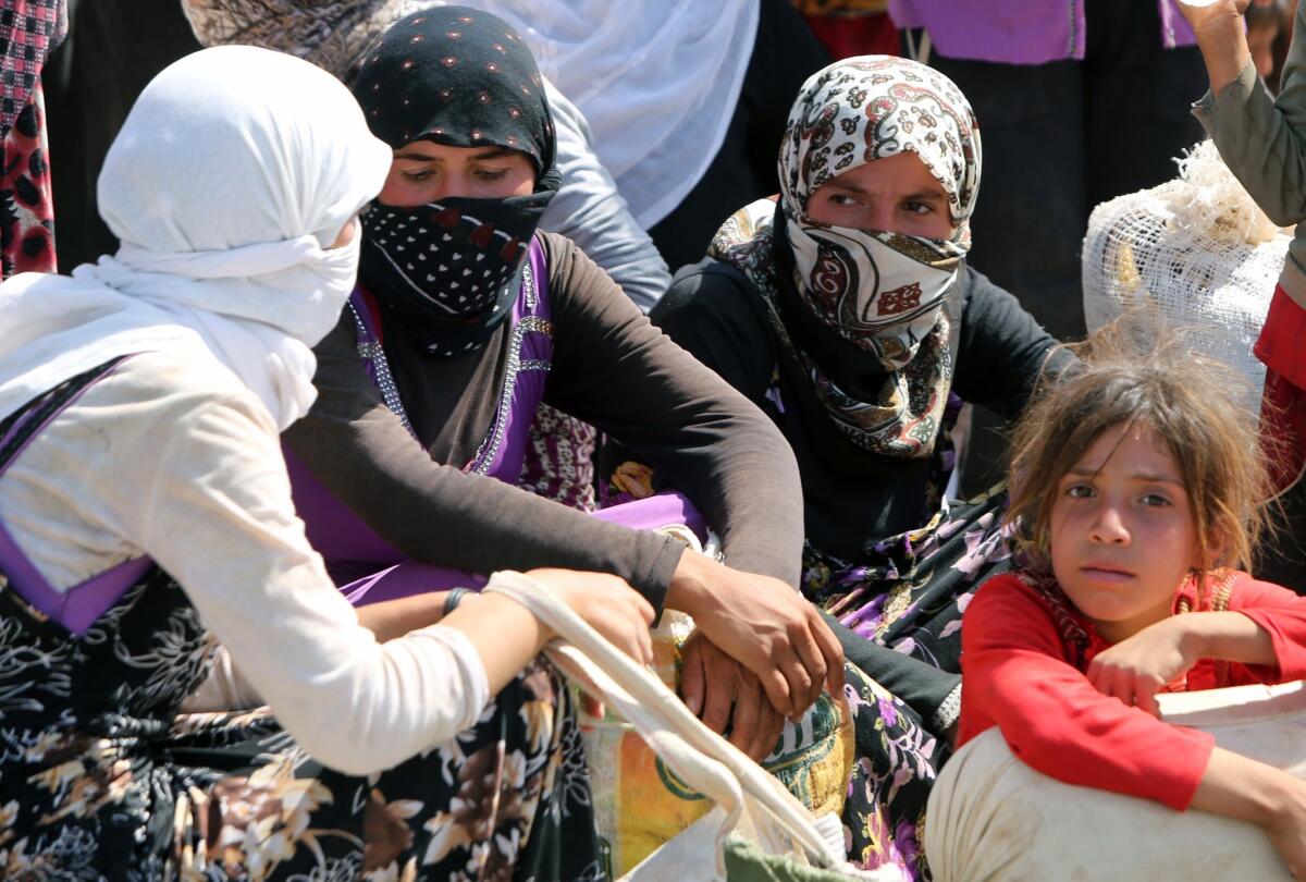 Islamic State militants killed scores of Yazidi men in a remote northern village and took hundreds of women and children captive, Iraqi officials reported. Above, displaced Yazidi women gather at a refugee camp in the semi-autonomous Kurdish region of Iraq on Aug. 13.