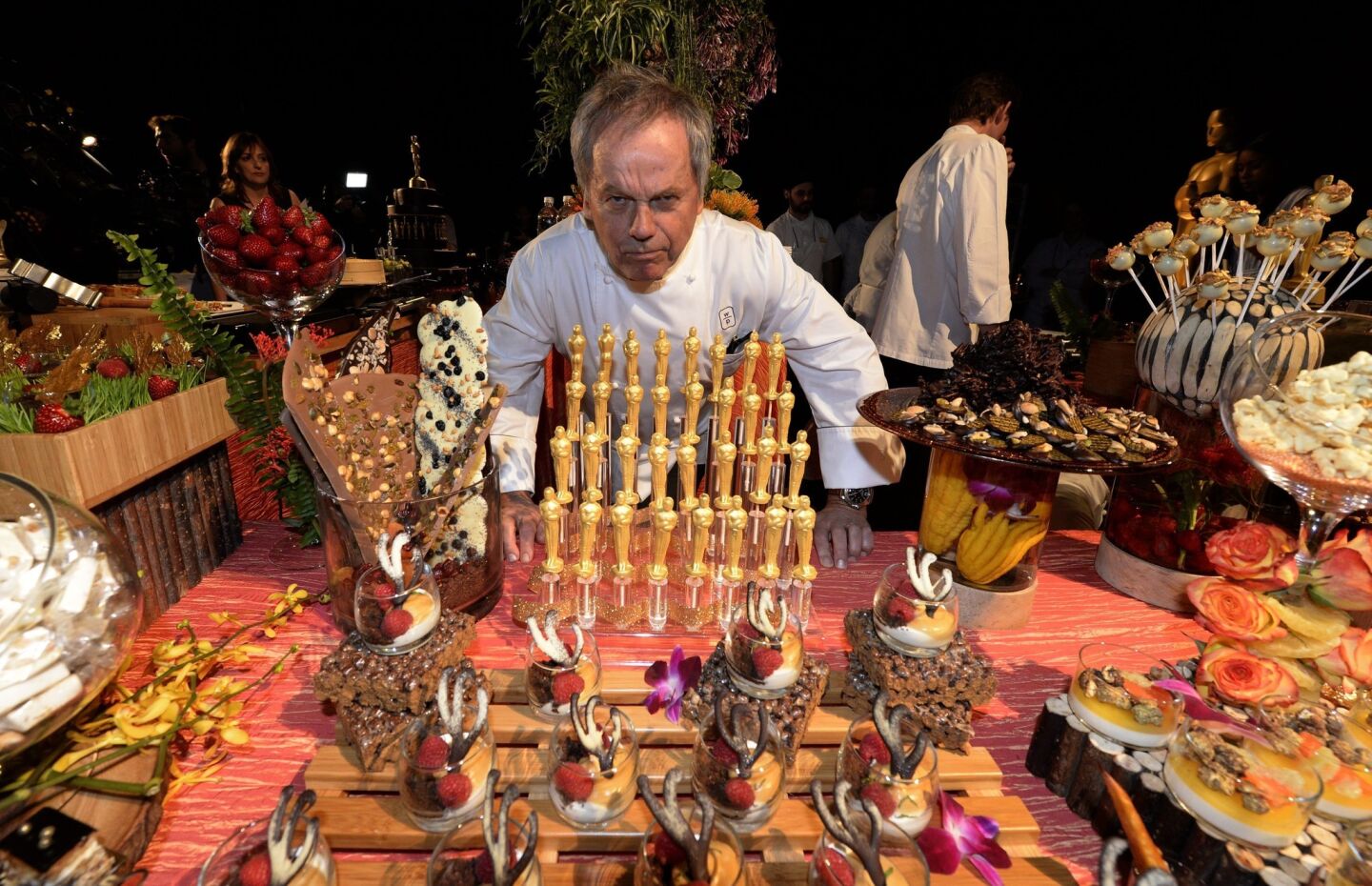 Wolfgang Puck poses with chocolate Oscar statuettes and a table of desserts destined for the Oscars Governors Ball.