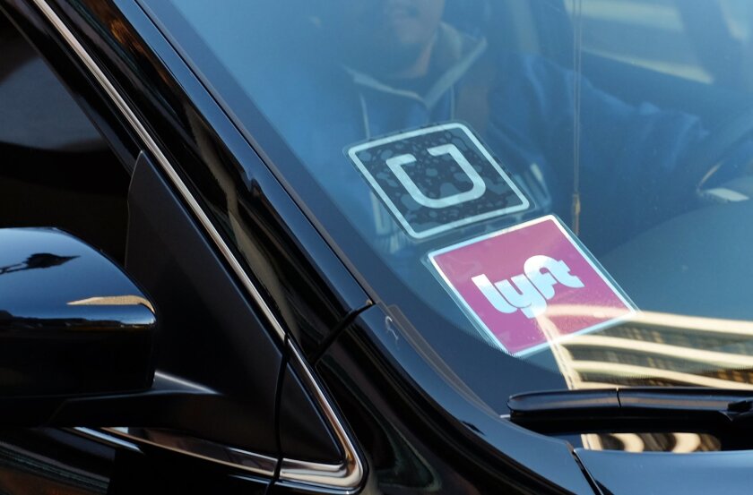  In this Tuesday, Jan. 12, 2016 file photo, a driver displaying Lyft and Uber stickers on his front windshield drops off a passenger in downtown Los Angeles, Calif. (AP Photo/Richard Vogel, File)
