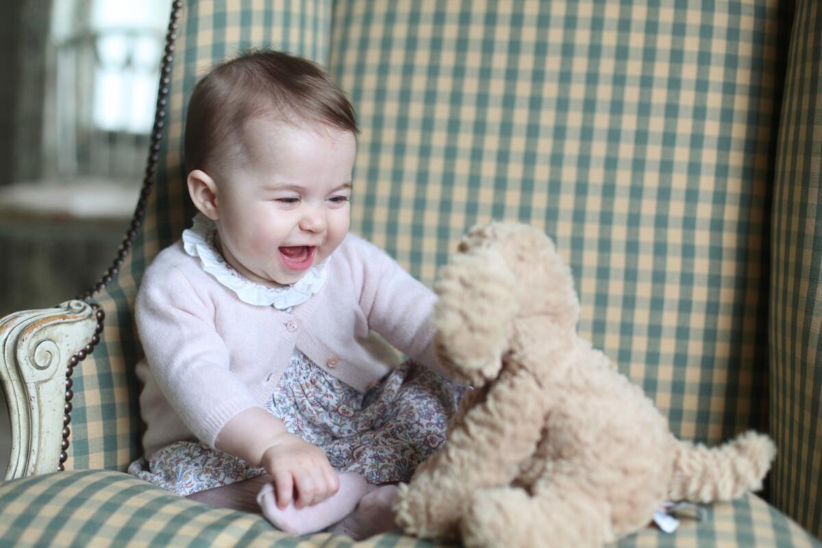 This undated photo released Sunday by Britain's duke and duchess of Cambridge shows Princess Charlotte with her cuddly toy dog at Anmer Hall in Norfolk, England.