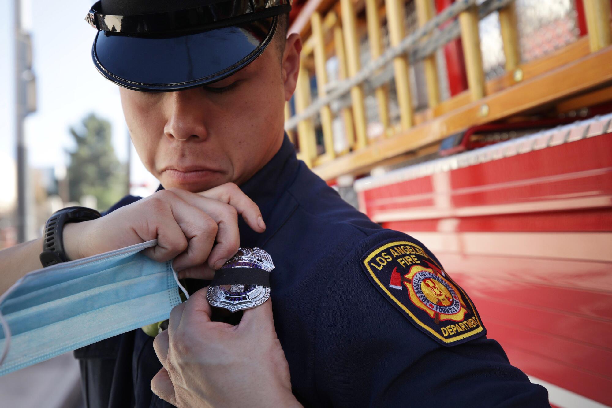 A firefighter attaches a black band to his badge on his uniform