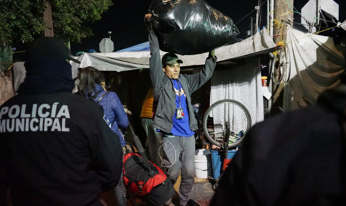Migrantes retiran sus pertenencias del albergue "El Chaparral" hoy, en Tijuana (México). 