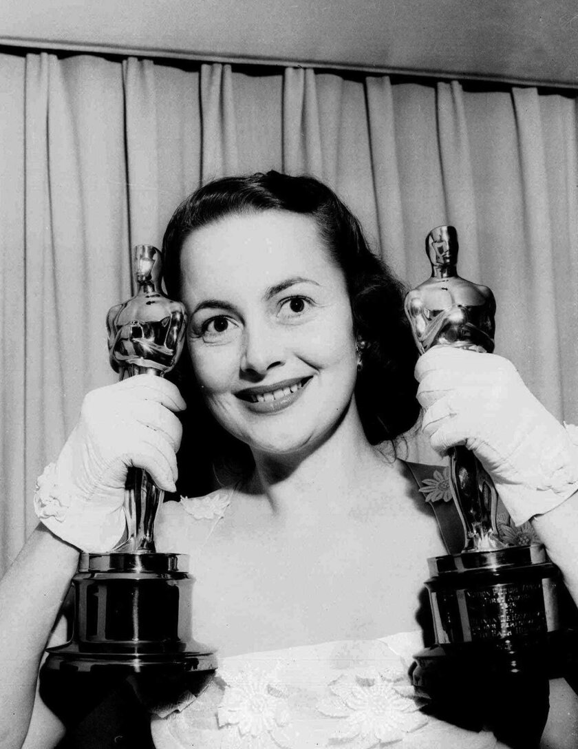 Olivia de Havilland holds her two Academy Award statuettes at her home after the Academy Awards ceremonies in March 1950.