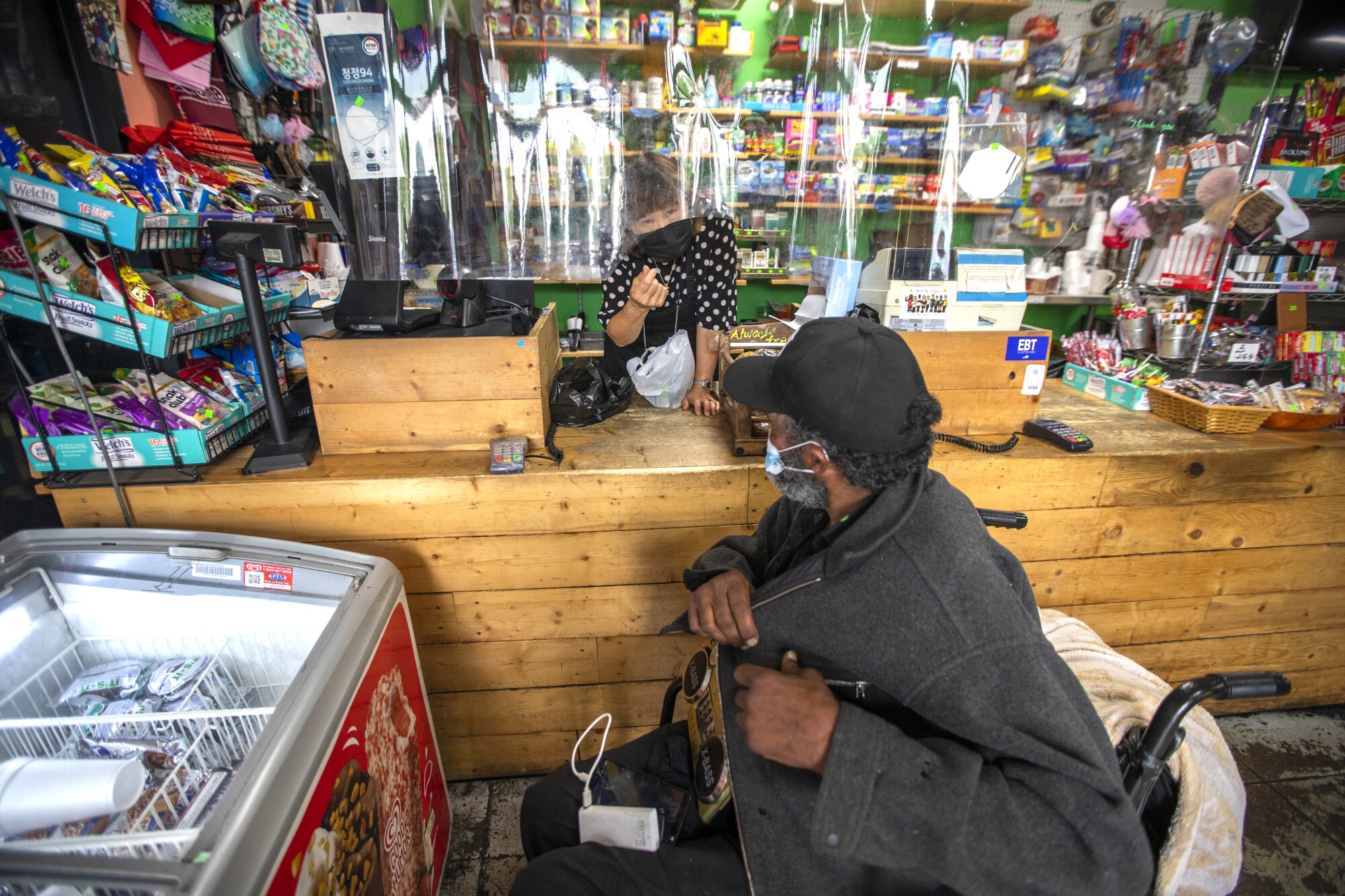 May Park, 67, speaks with a customer in a wheelchair as she works at Skid Row People's Market 