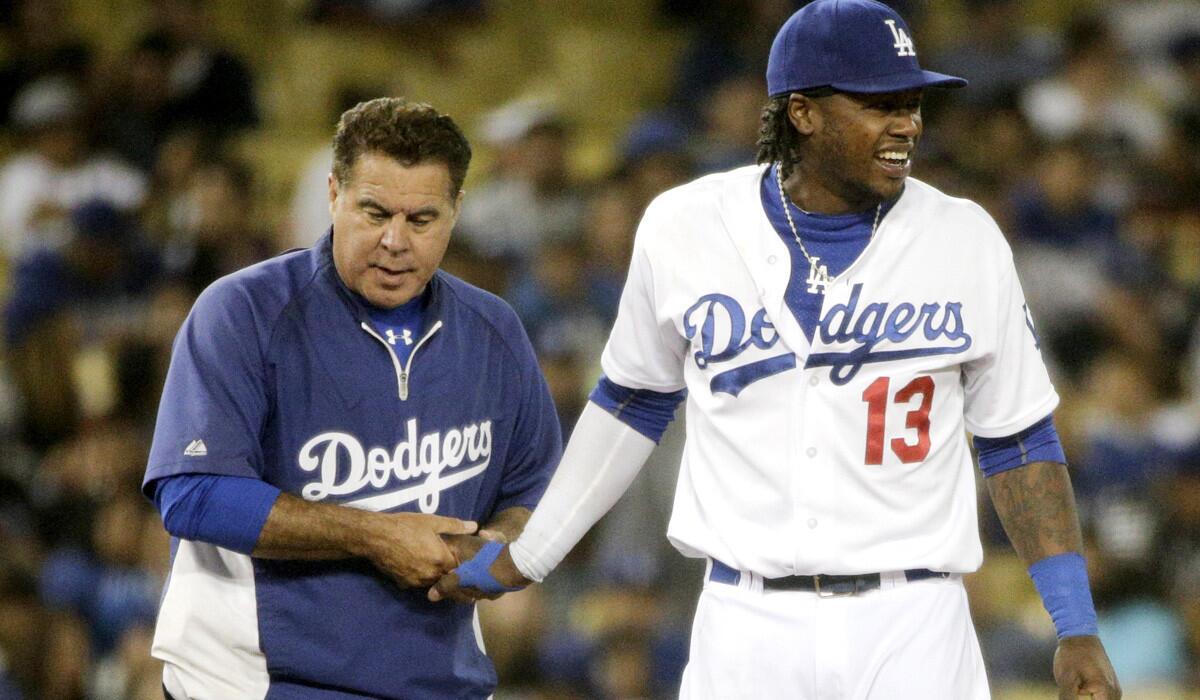 Dodgers shortstop Hanley Ramirez grimaces as trainer Stan Conte checks on his injured finger in the seventh inning of a game against the Rockies on Tuesday night.