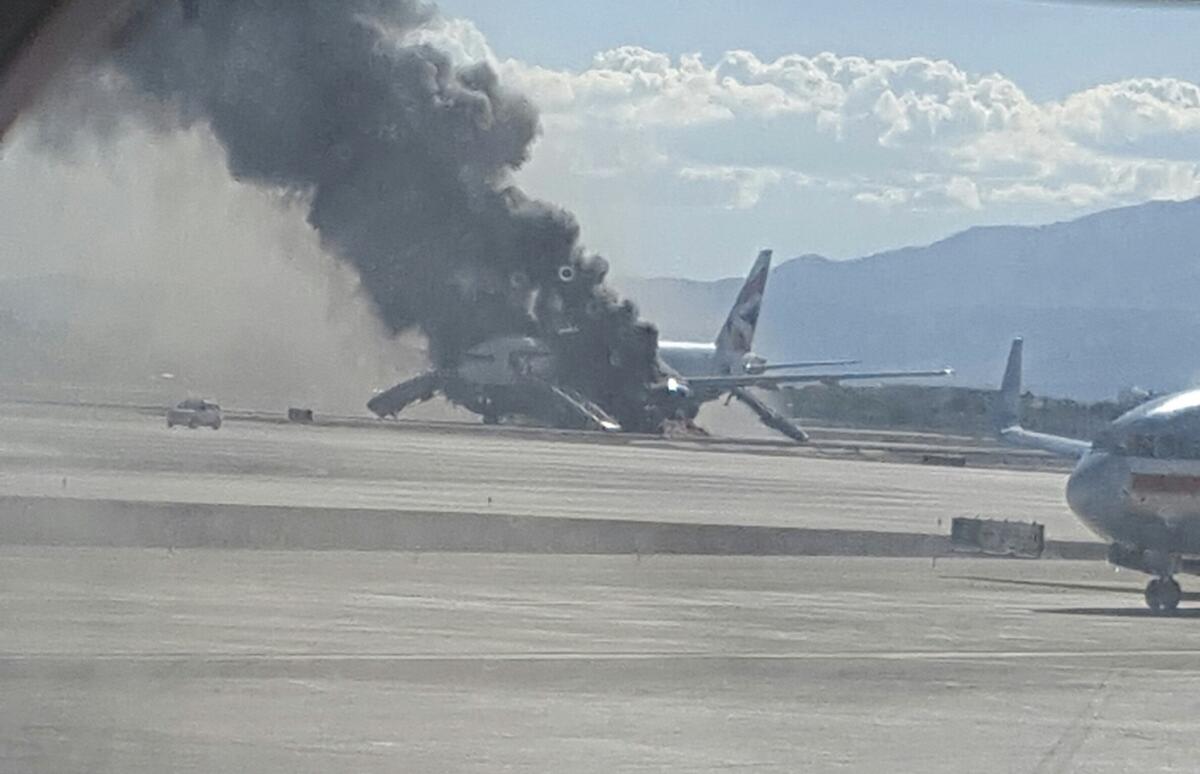 In this photo taken from another plane window, smoke billows from an aircraft that caught fire at McCarren International Airport in Las Vegas.