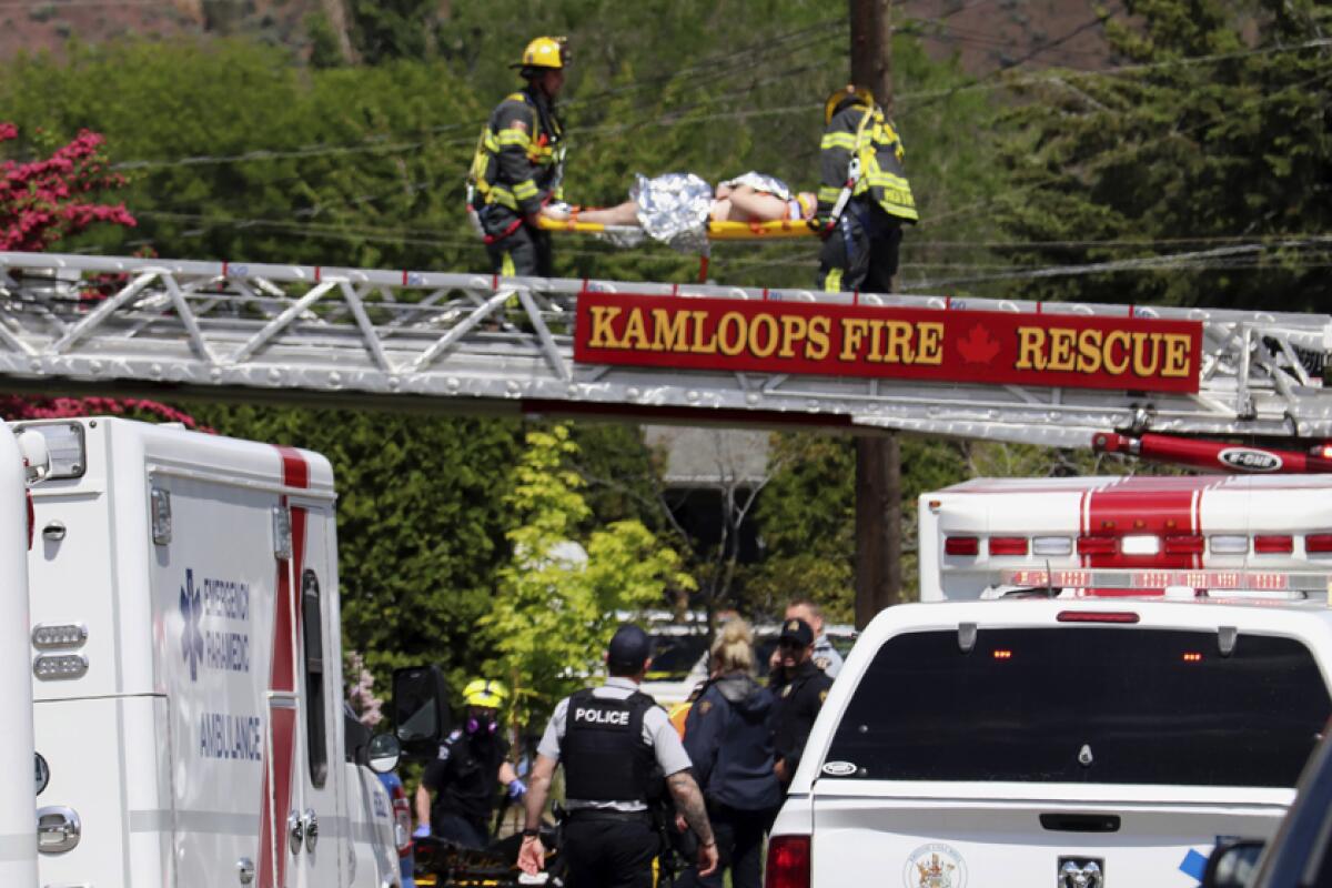 An injured person is carried across a firetruck ladder after being rescued from a rooftop following the crash of an aerobatic jet in Kamloops, Canada, on Sunday.