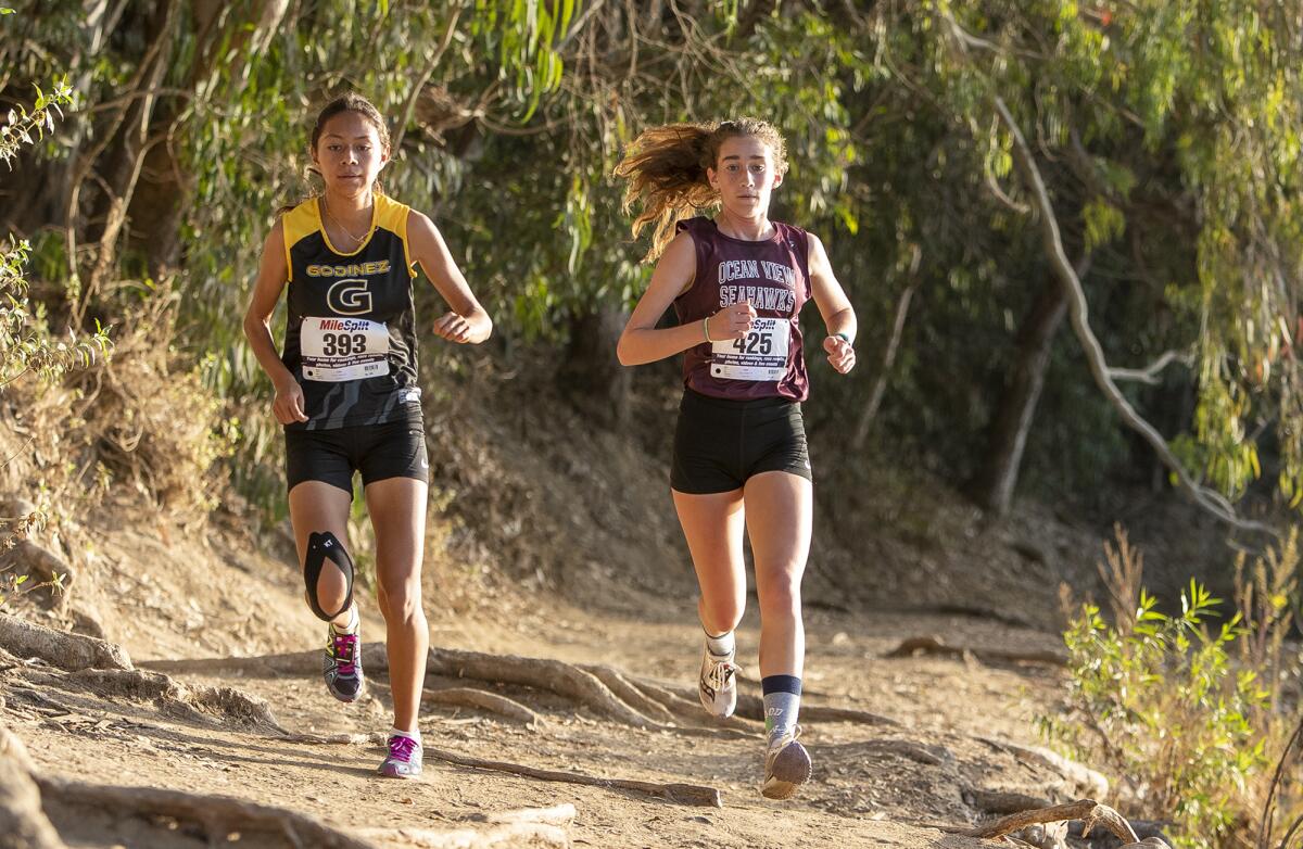 Ocean View's Elizabeth King, right, and Godinez's Yuliana Carrera run in a technical section of the trail during the Golden West League girls' finals at Central Park in Huntington Beach on Wednesday.