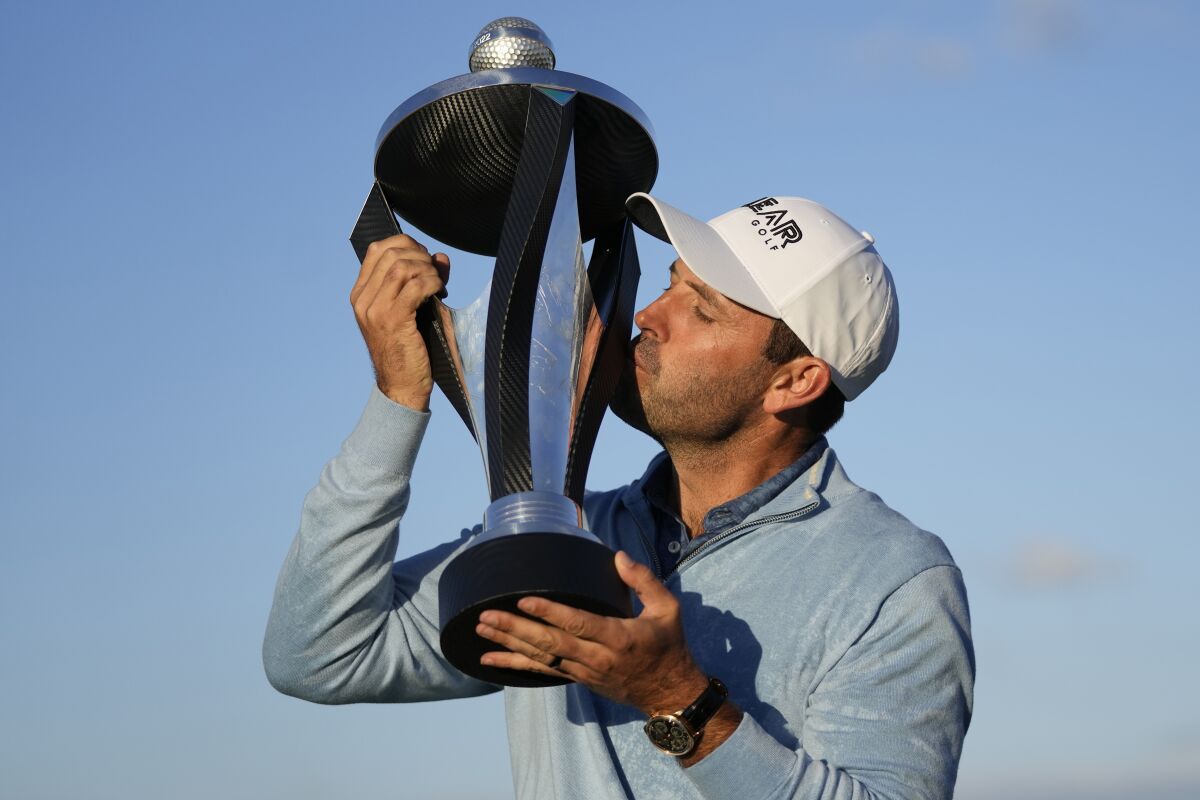 Charles Schwartzel of South Africa kisses the trophy after winning the inaugural LIV Golf Invitational.