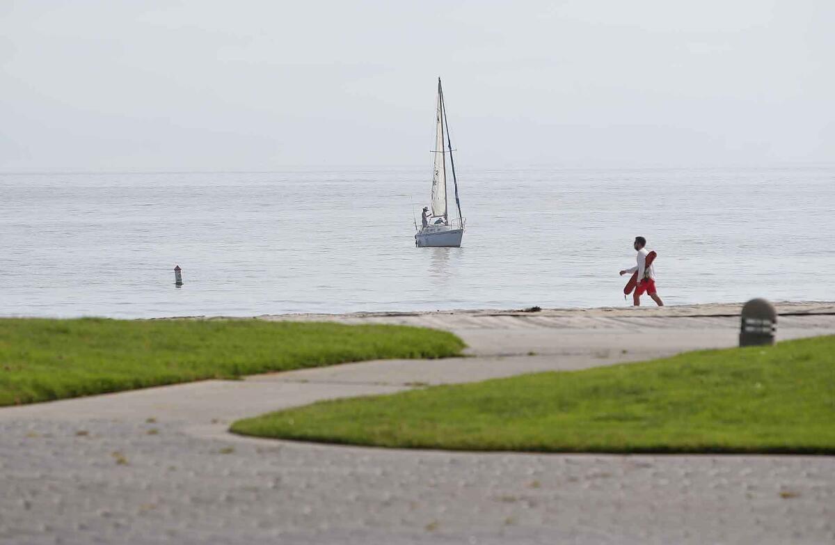 Paths and the grass remain empty, as only a lifeguard and sailboat occupied Main Beach on Sunday while Laguna Beach city beaches remained closed due to the coronavirus pandemic.