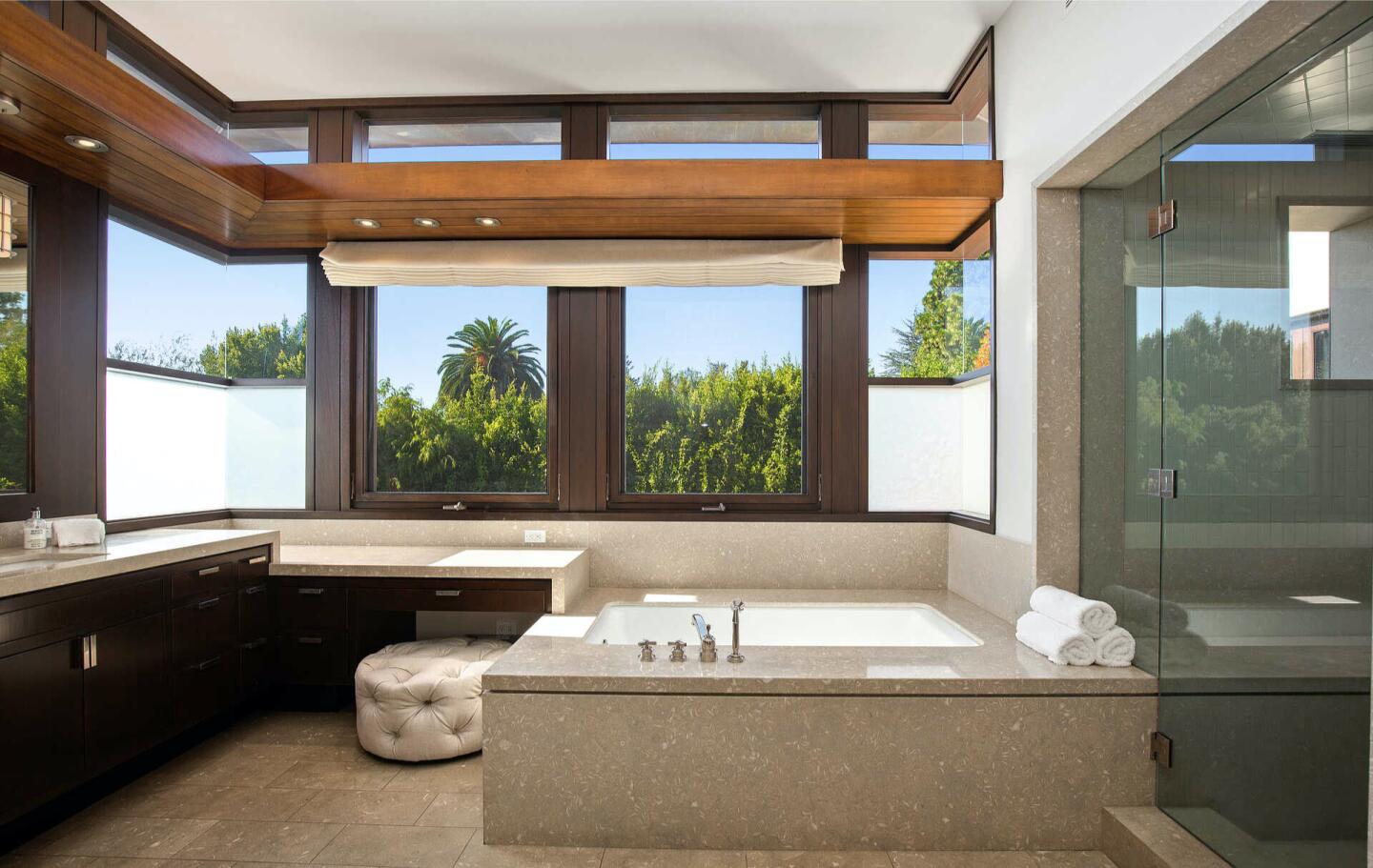 The bathroom with a tub and sink and windows overlooking trees.