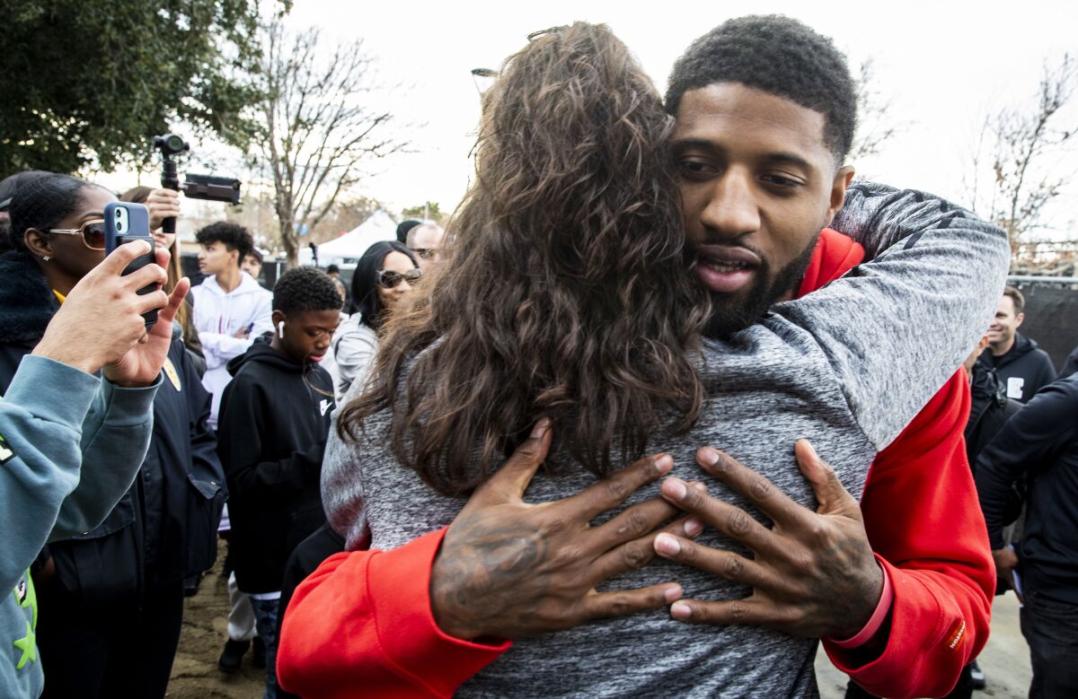 Clippers star Paul George hugs a supporter after unveiling refurbished basketball courts at Domenic Massari Park in Palmdale on Sunday.