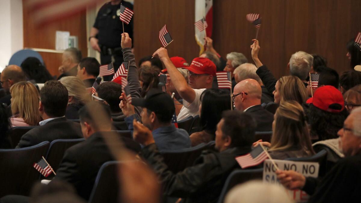 Opponents of Senate Bill 54 cheer and wave American flags Tuesday night during a Costa Mesa City Council discussion on whether to take an official stand against the “sanctuary state” law.