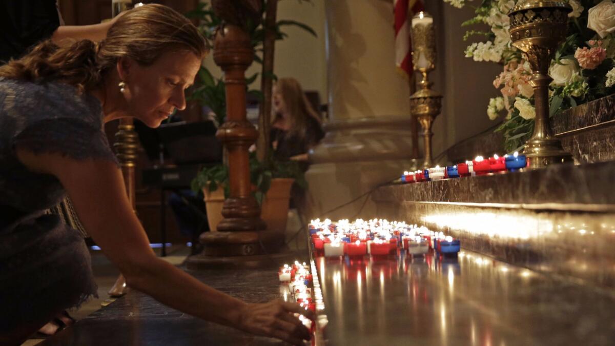 A woman places a candle on the altar during a prayer service for the victims of the Grand 16 theater shooting at the Cathedral of St. John the Evangelist, in Lafayette, La., on July 26, 2015.