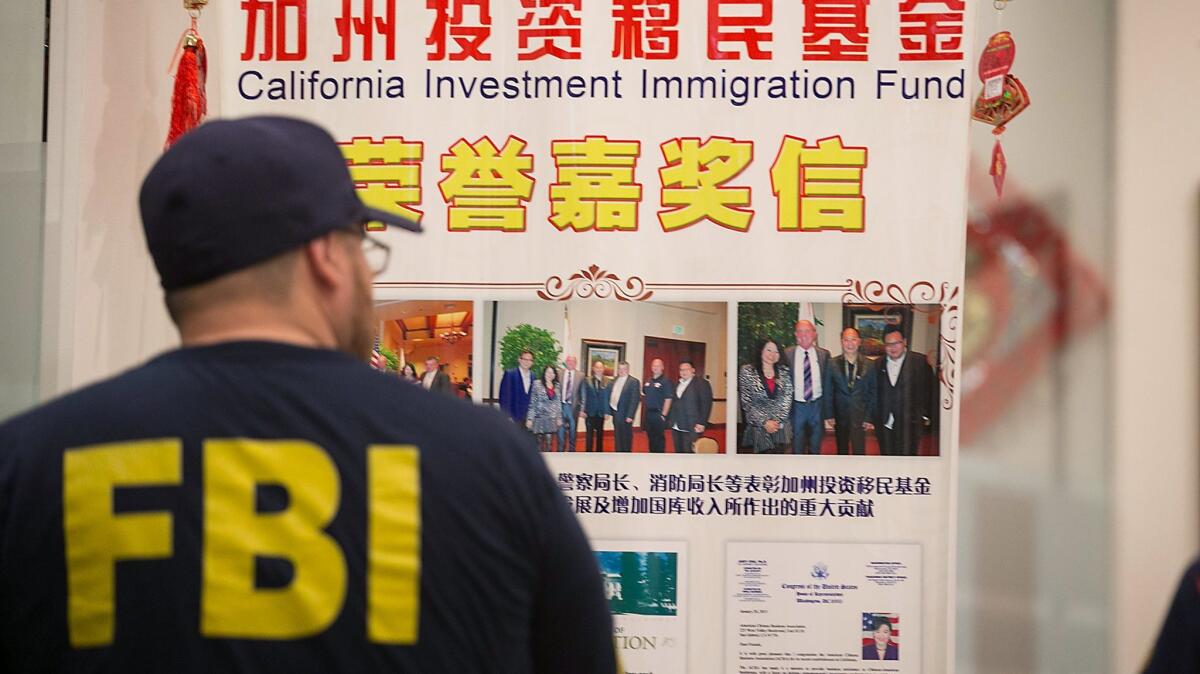 An FBI agent earlier this year searching the lobby of a San Gabriel Valley company that authorities alleged was used by an attorney and her father to run an immigration fraud scheme that netted tens of millions of dollars.