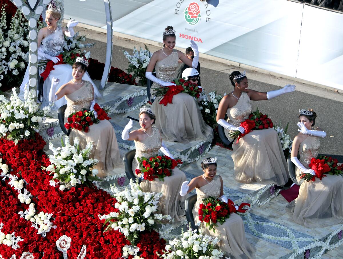 Members of the 2020 Tournament of Roses Royal Court wear gowns and tiaras, hold roses, wave and sit on a float. 
