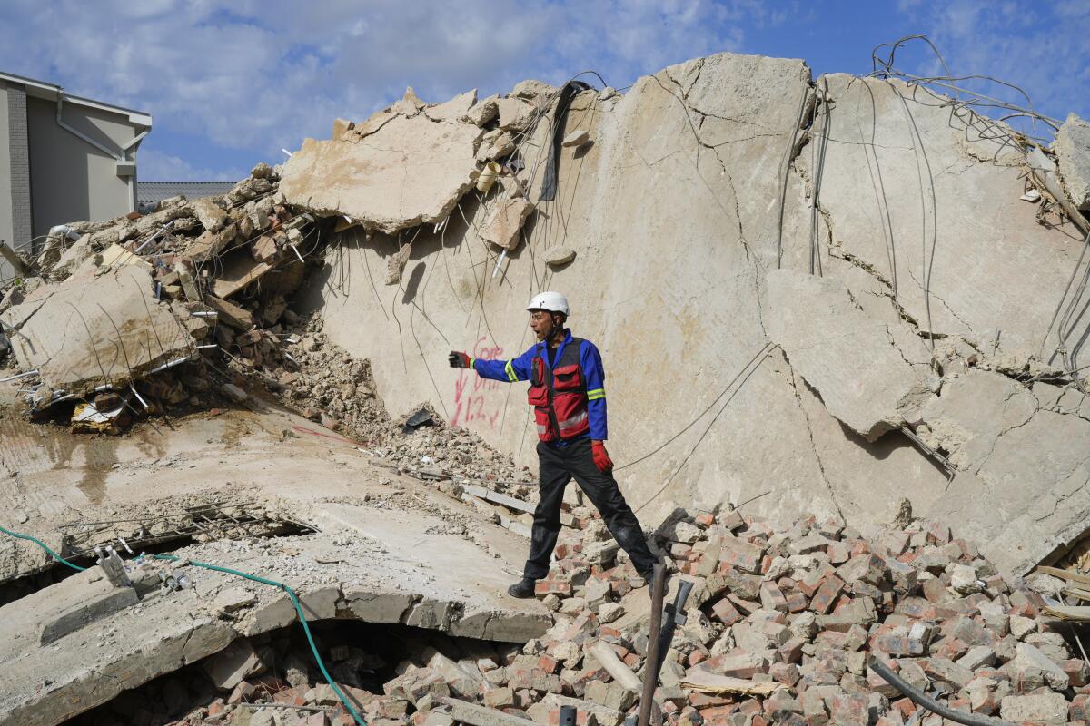 A rescue worker stands atop a pile of broken concrete and bricks