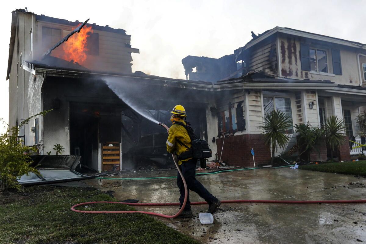 A firefighter sprays water on a house fire