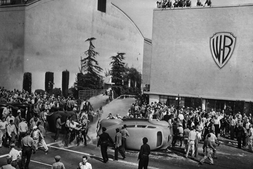Oct. 5, 1945: Strikers outside of employee entrance to Warner Brothers Studios in Burbank. Strikers and non-strikers clashed in fights as non-strikers tried to cross picket line. Studio firemen, center, background, turn hose on battlers. Two workers’ cars and officers’ car, at the left, were overturned as they attempted to enter the studio. This photo appeared in the Oct. 6, 1945, Los Angeles Times.