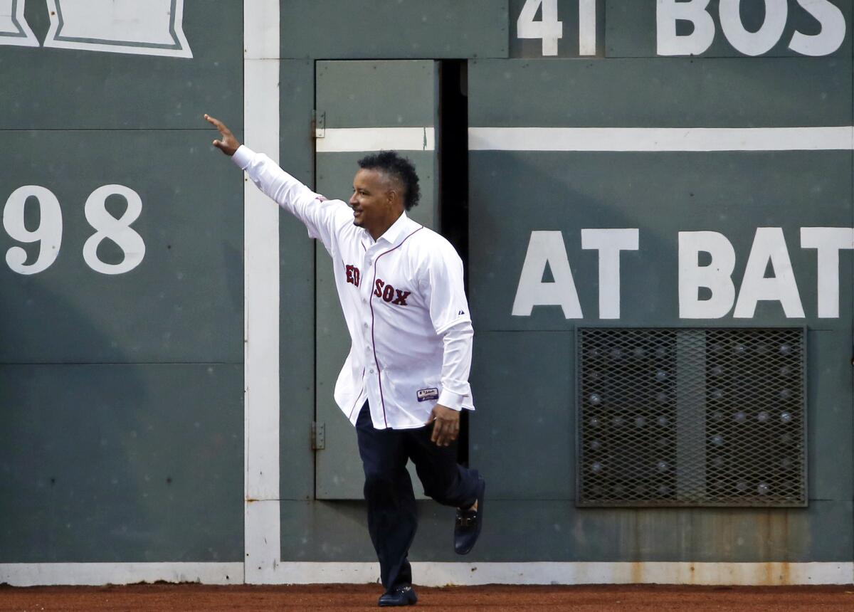 Manny Ramirez emerges from the Green Monster door in left field at Fenway Park to a loud ovation during a celebration of the 2004 World Series champion Red Sox team on Wednesday.