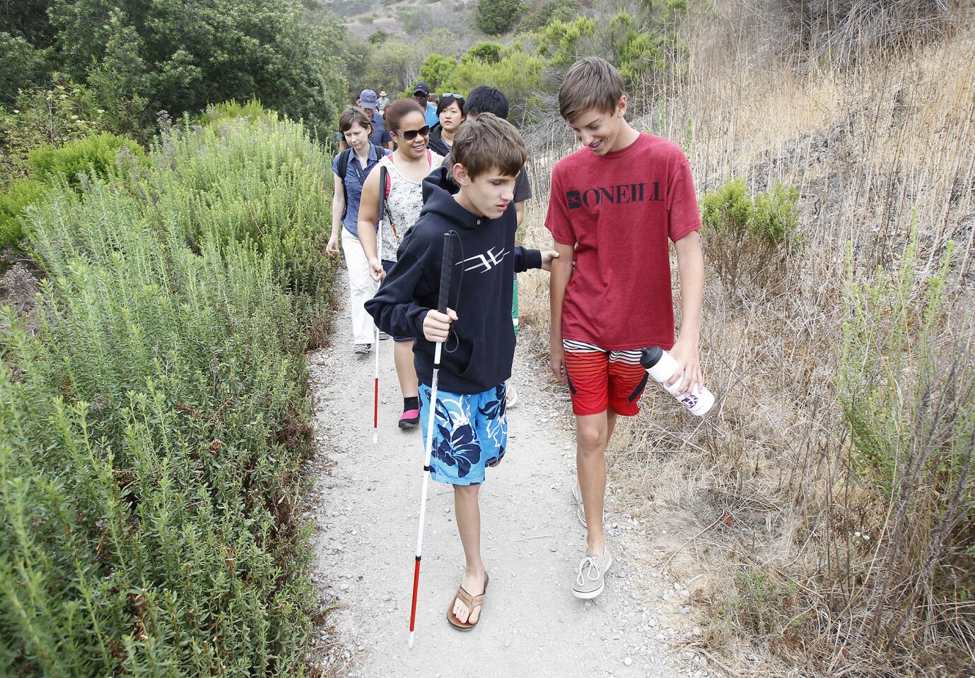 Sight impared brothers Sam, left, and Ben Blatchfield walk confidently down the Study Loop trail with fellow Braille Institute students at Crystal Cove on Thursday.