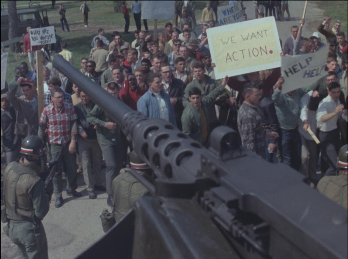 People hold up posters and chant in an image from the documentary "Riotsville, USA."