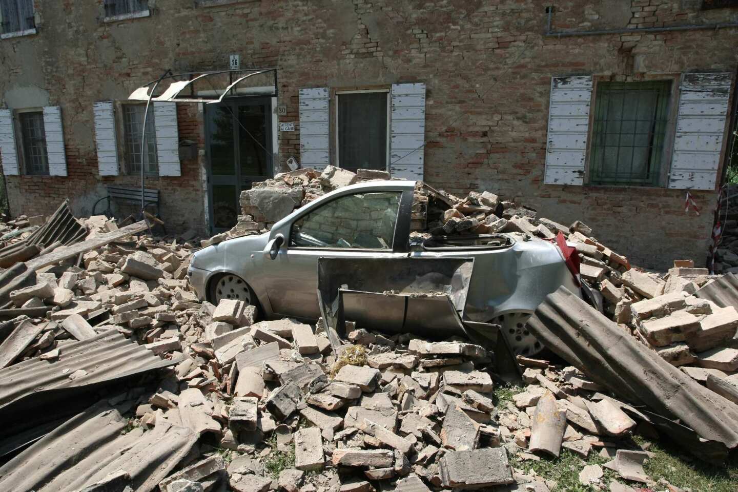 A car is surrounded by the rubble of a collapsed roof after an earthquake in Cavezzo, just days after another quake in the same region.
