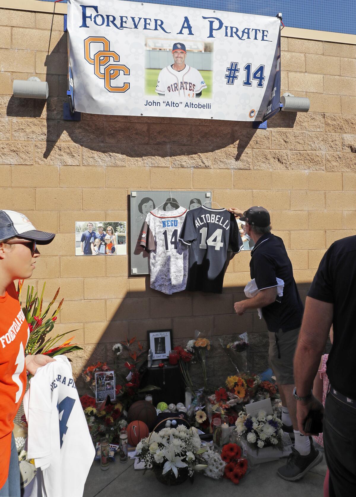 A man hangs a baseball jersey of late longtime Orange Coast College baseball coach John Altobelli before Tuesday's game against Southwestern College. Altobelli his wife, Keri, and daughter, Alyssa, were among the nine people who died in a helicopter crash on Sunday in Calabasas.