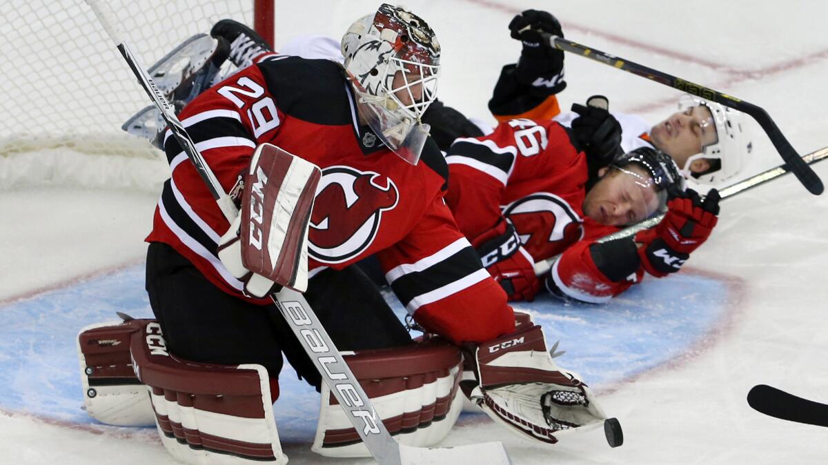 Then-New Jersey goalie Anders Lindback loses the puck as the Devils' Karl Stollery (46) and Philadelphia's Scott Laughton crash into him during an exhibition game on Sept. 26.