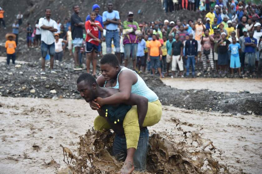 A man carries a woman across a river at Petit Goave where a bridge collapsed during the rain from Hurricane Matthew, southwest of Port-au-Prince, Haiti.