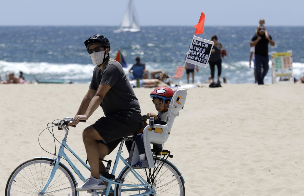 A cyclist and his passenger fly a Black Lives Matter banner in Venice Beach on Sunday.