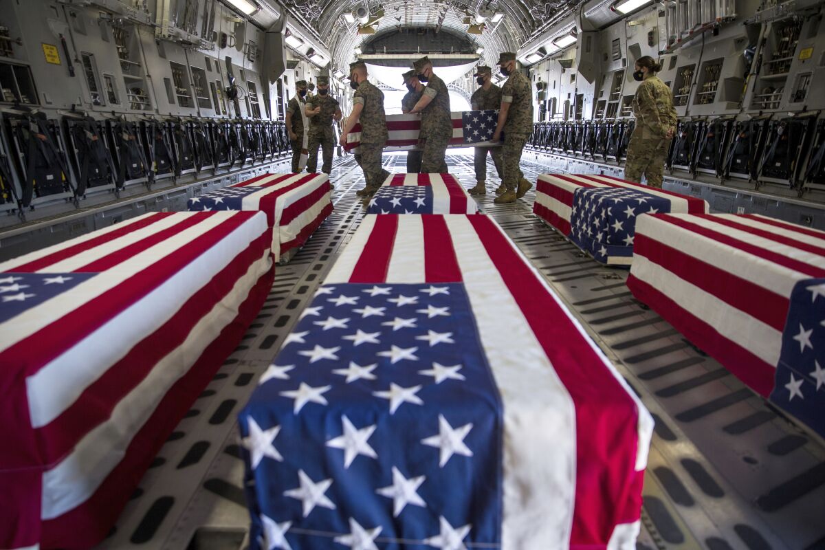 In this photo provided by the U.S. Marine Corps, U.S. Marines and sailors carry a casket inside a U.S. Air Force C-17 Globemaster III at Marine Corps Air Station Miramar, in Calif., Wednesday, Aug. 12, 2020. The remains of seven Marines and a sailor, who died after a seafaring tank sank off the coast of Southern California last month, were transferred to Dover Air Force Base in Delaware for burial preparations. (Lance Cpl. Brendan Mullin/U.S. Marine Corps via AP)