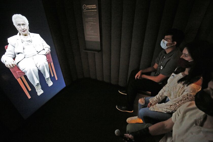 LOS ANGELES, CA - JULY 29: Students Jacob Manela, Sophia Kangavari and Will Spangler, left to right, interact with 97-year-old Holocaust survivor Renee Firestone -- one of the oldest remaining such survivors in the world appearing in "Dimensions in Testimony," which gives visitors the opportunity to have a virtual "one-on-one" conversation with Renee as a Holocaust survivor. The pioneering project integrates advanced filming techniques, specialized display technologies and next-generation natural language processing to create an interactive biography so there viewer can receive real-time responses to questions from pre-recorded video images. "Our museum was founded by survivors who wanted to share their stories publicly and educate the next generation," said Beth Kean, CEO of the Museum. "With 'Dimensions in Testimony,' countless future generations of visitors and students can hear those stories from the survivors and learn directly from those who were there, even when they are no longer with us." Holocaust Museum on Thursday, July 29, 2021 in Los Angeles, CA. (Al Seib / Los Angeles Times).