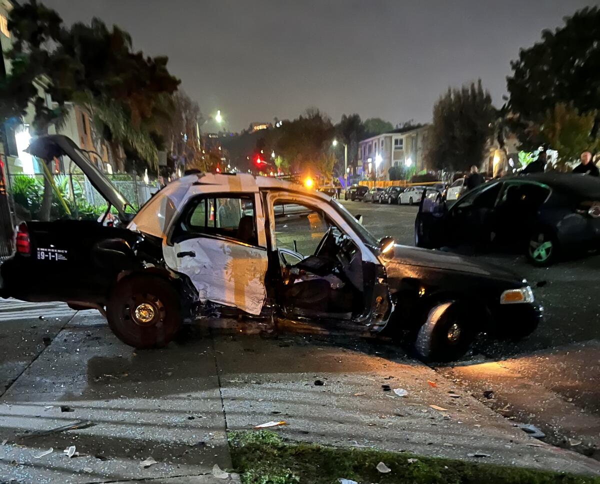A wrecked LAPD car with a door missing and debris surrounding it