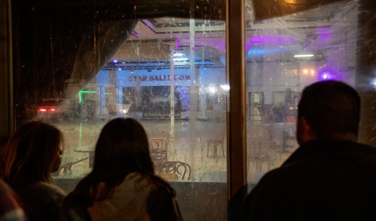 Bystanders peer inside a window at Star Ballroom Dance Studio in Monterey Park.