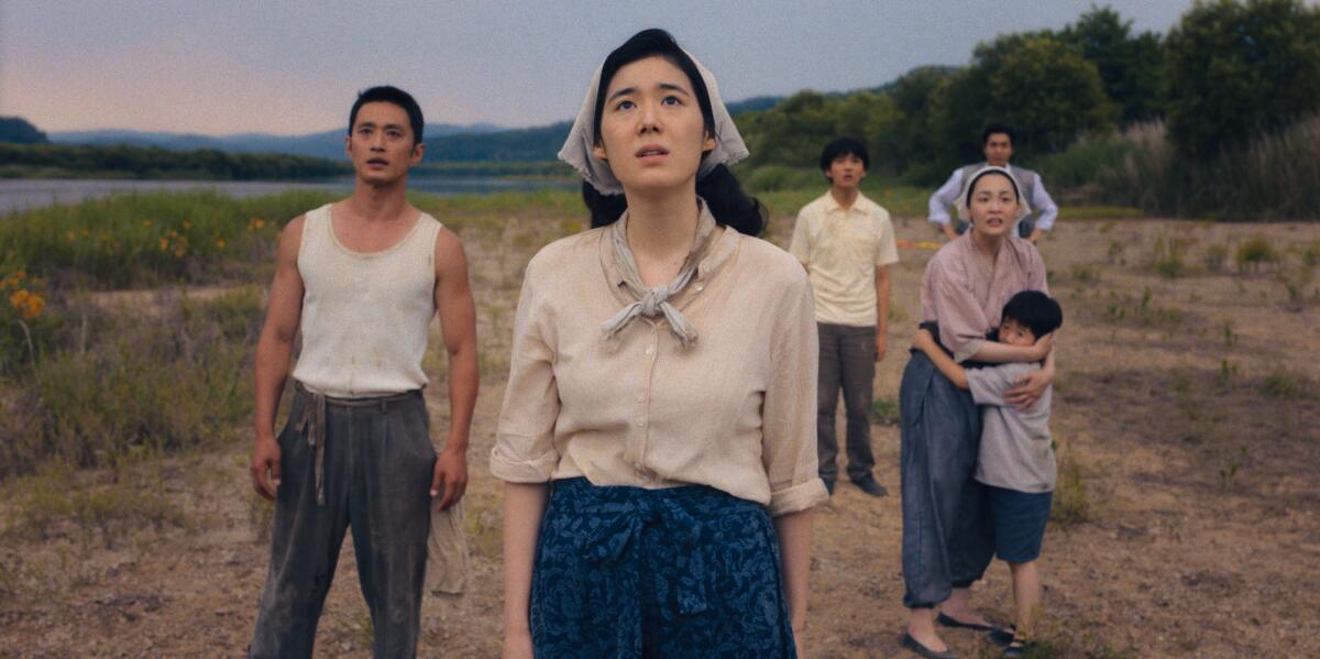 A group of people standing in a field looking upward toward the sky.