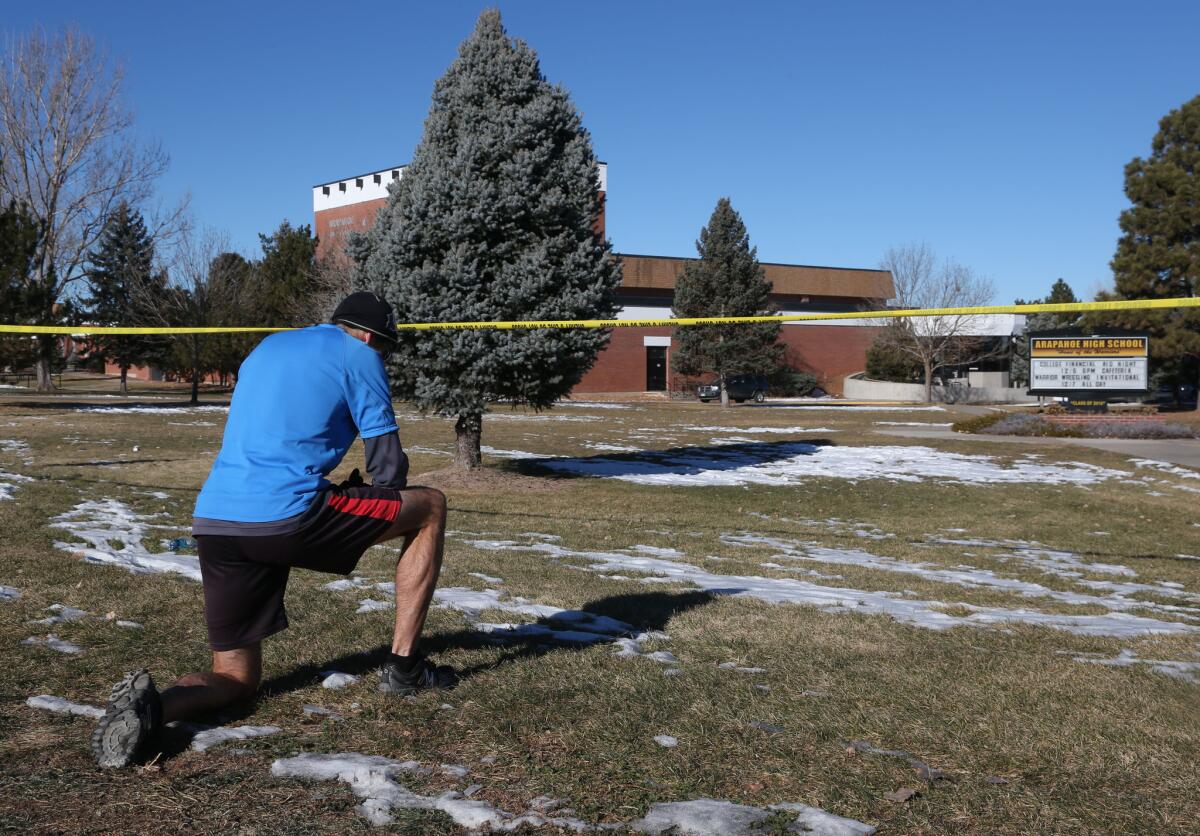 Sean Sweeney, a runner who lives near Arapahoe High School in Centennial, Colo., pauses Saturday to say a prayer outside the school that was terrorized by a gunman Friday.