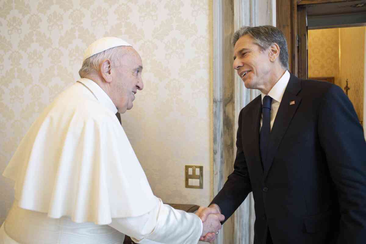Pope Francis and Secretary of State Antony J. Blinken smile and shake hands at the Vatican.