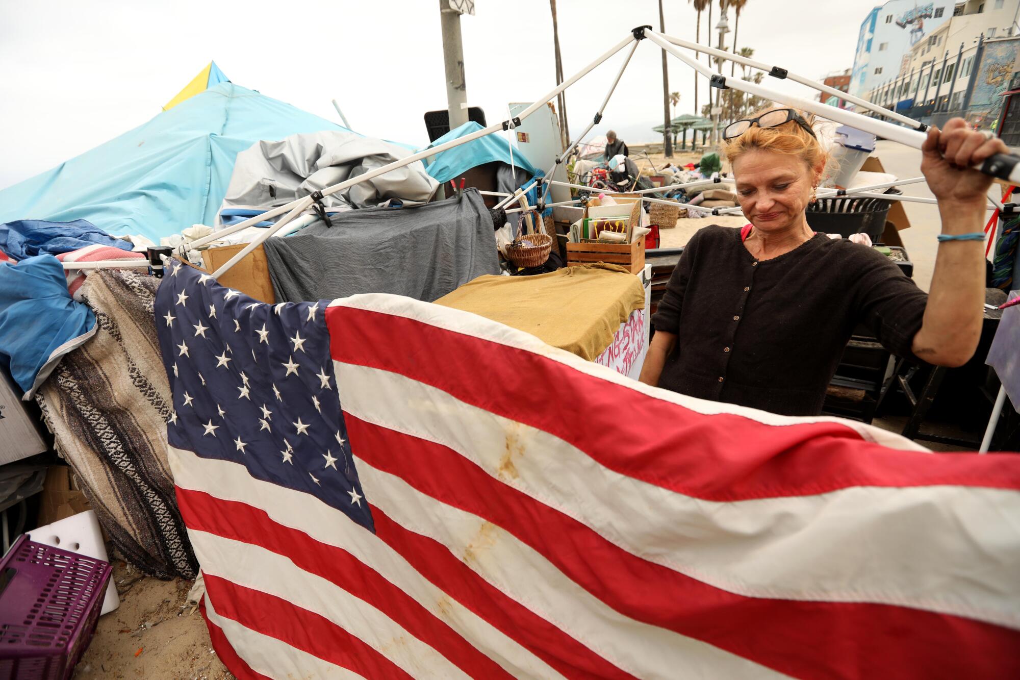 Dixie Moore, 47, who is homeless, assesses her situation before trying to move her encampment in Venice.