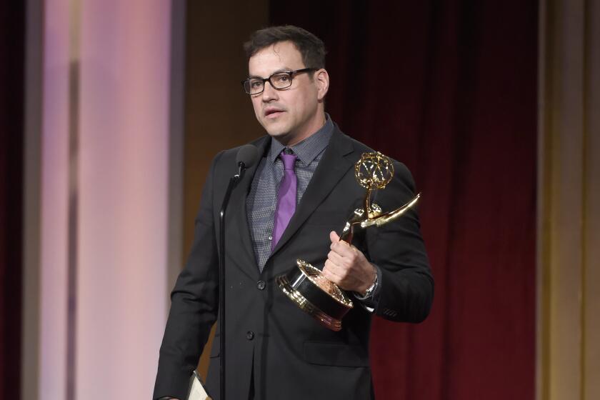 Tyler Christopher accepts a Daytime Emmy Award on stage while wearing glasses and a dark suit