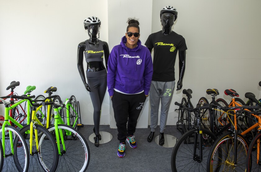 Kellie Hart is flanked by bikes and two mannequins dressed for cycling. 